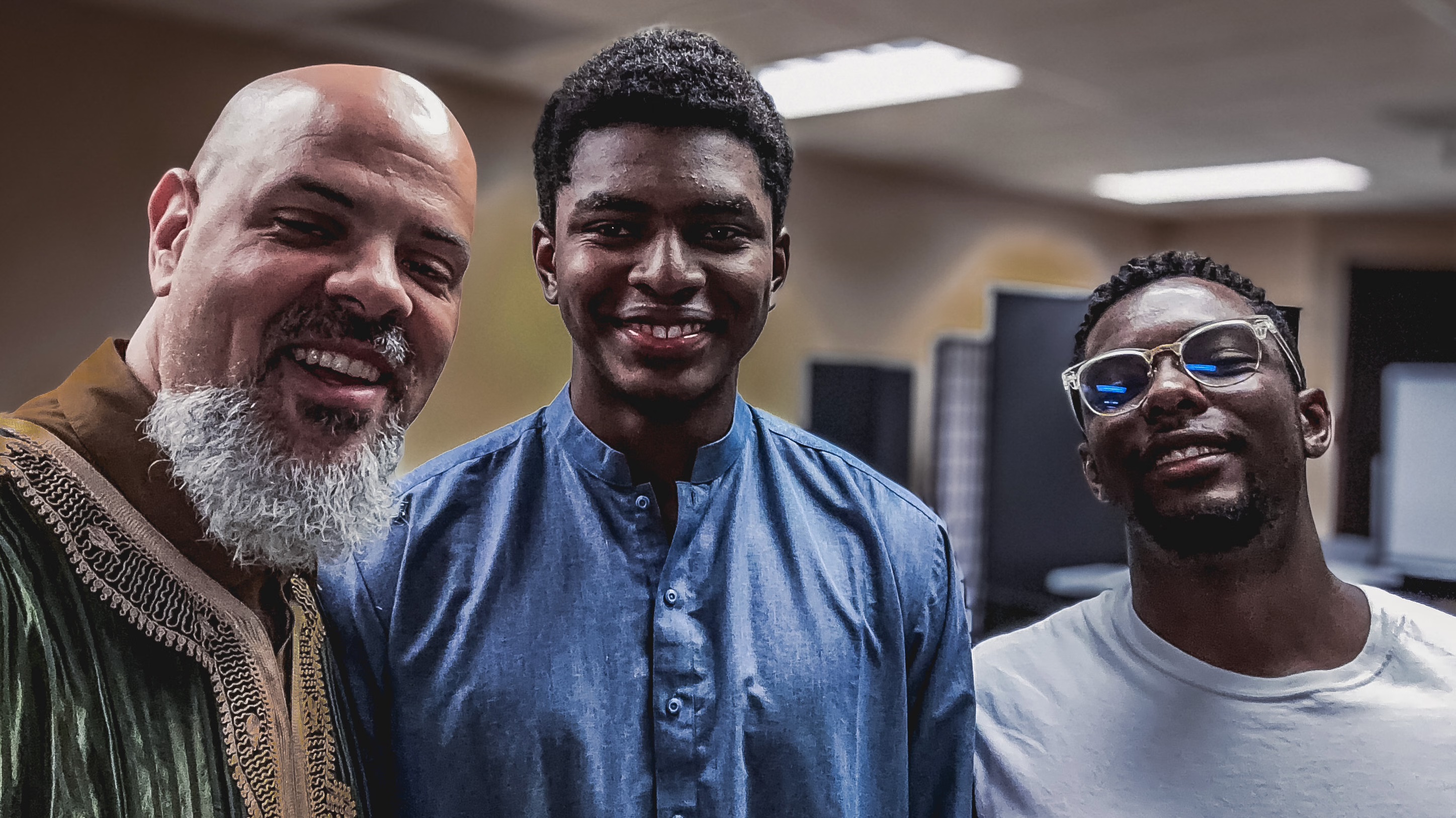 Imam Marc Manley smiling with two young men from the Middle Ground community