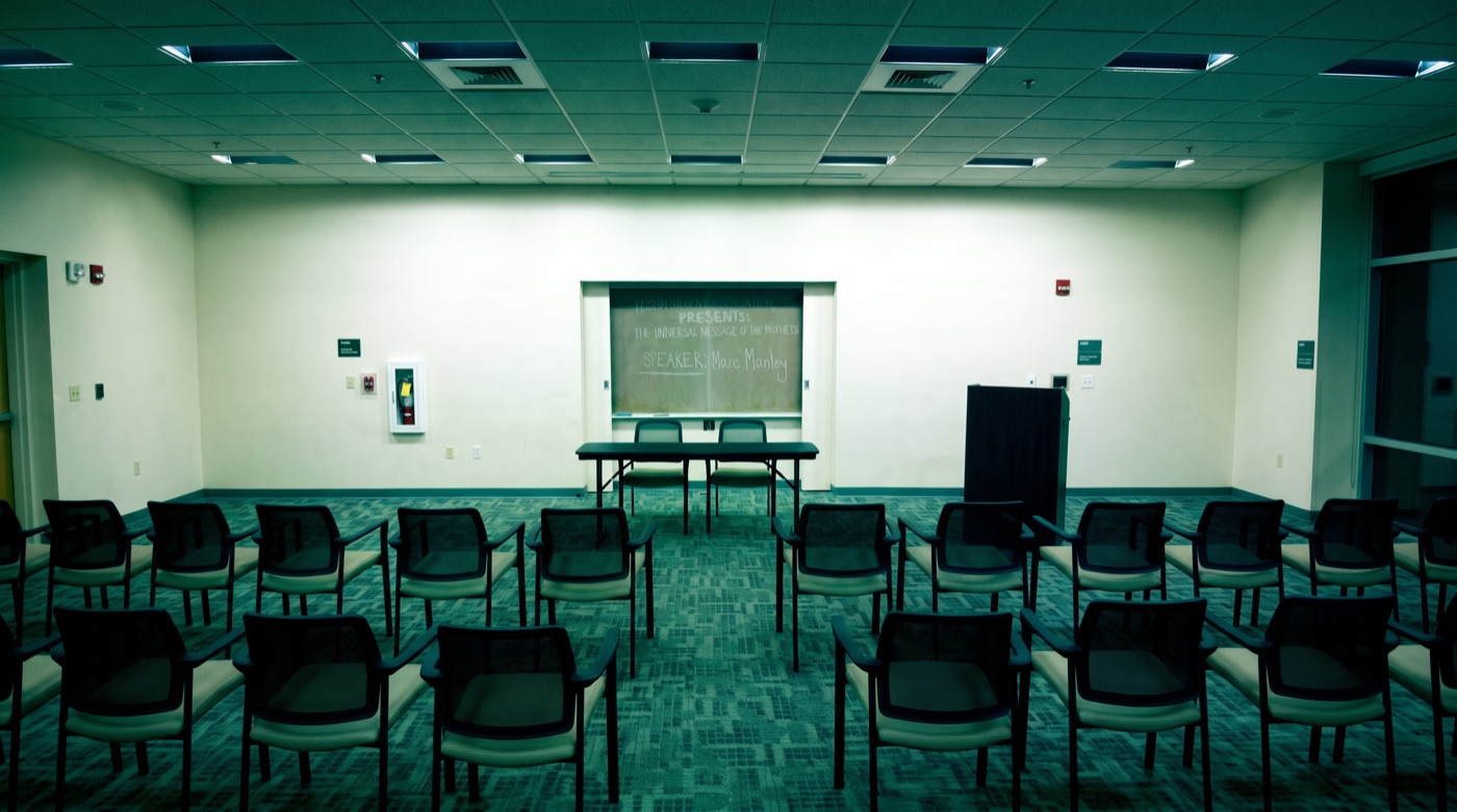 An empty lecture hall in Philadelphia, chalkboard reading &ldquo;The Universal Message of the Prophets, Speaker: Marc Manley&rdquo;